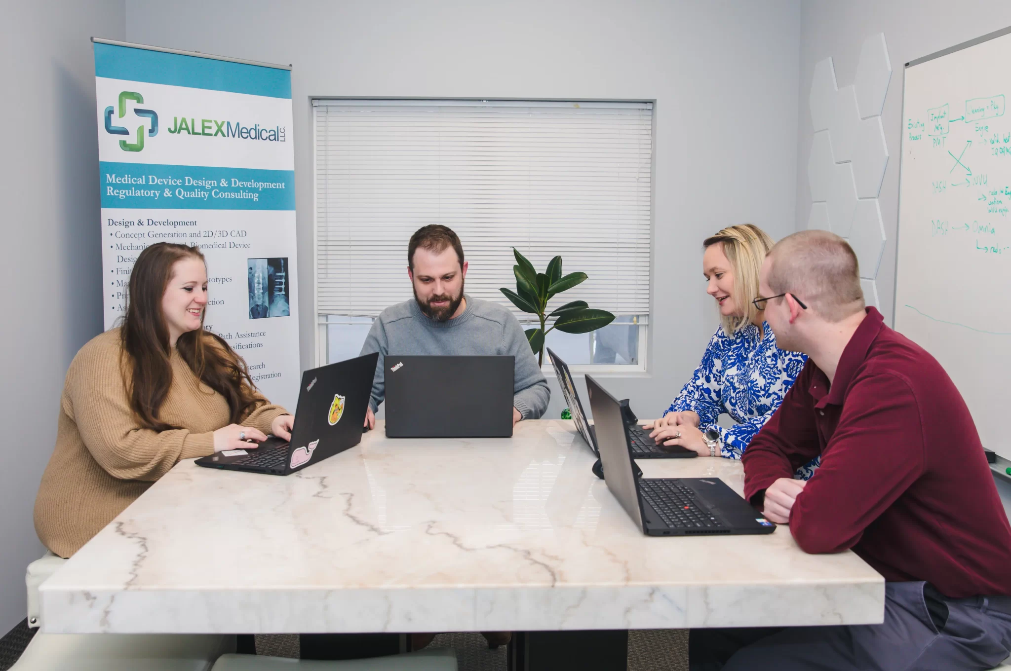 Medical device consulting team meeting with laptops in conference room at JALEX Medical