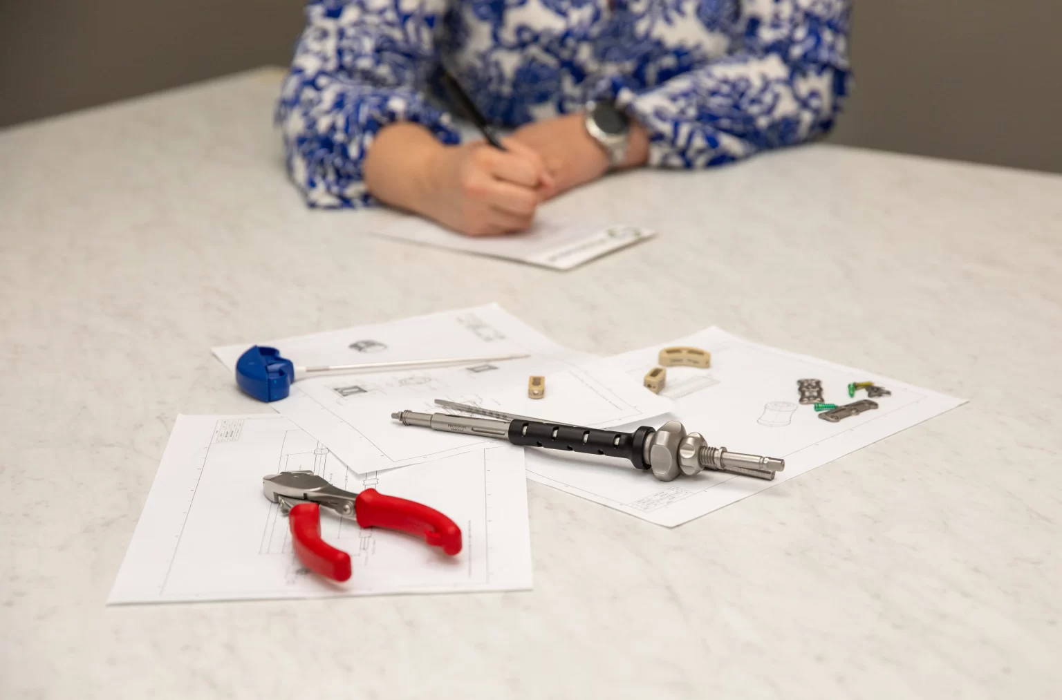 Medical device engineering tools and implant components displayed on design drawings during development meeting